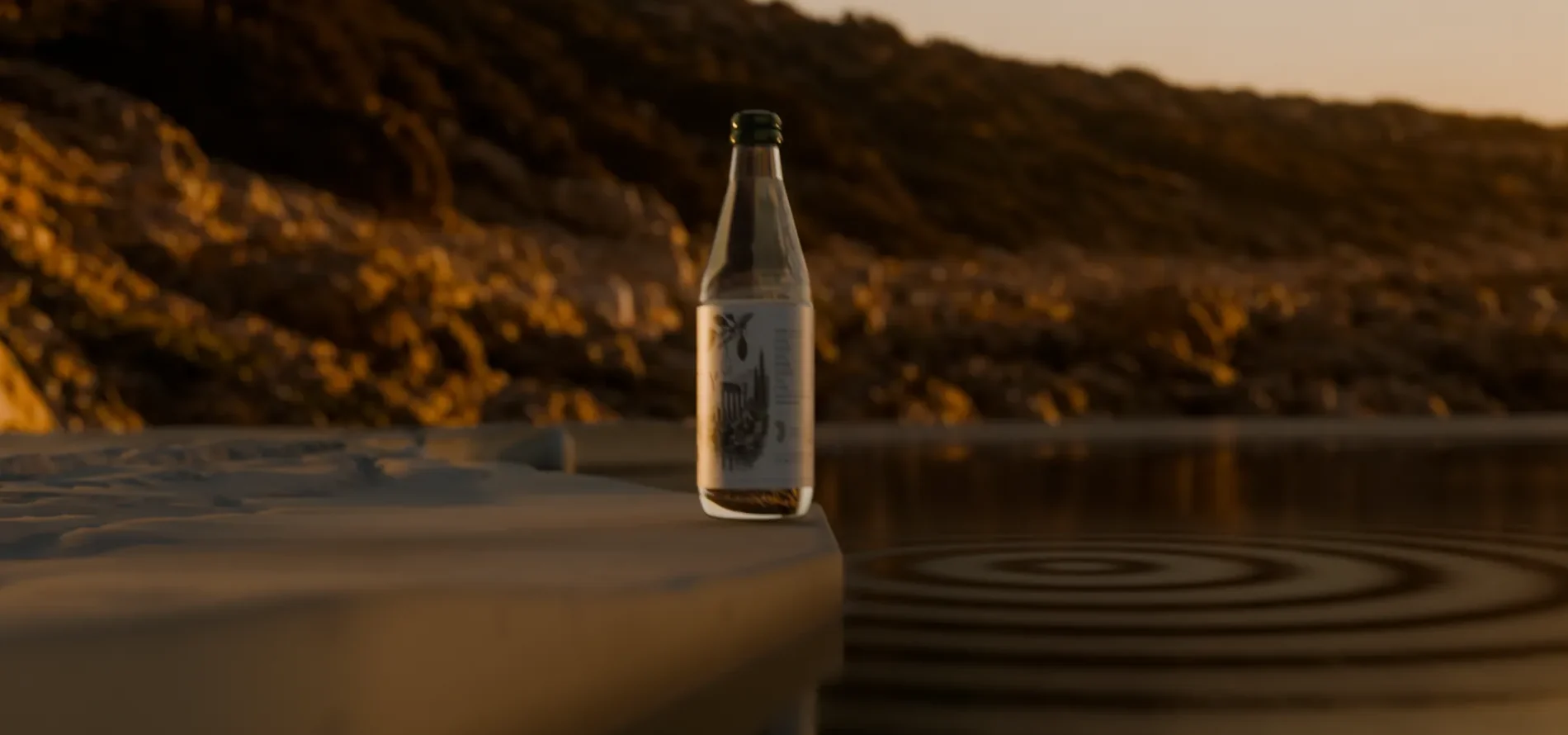 A Mastry bottle on a stone ledge above still water, dry scrub hillside behind, late afternoon